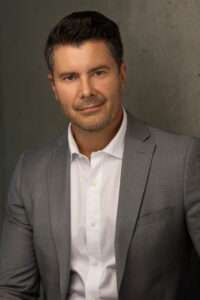 Full-length image of Mark A. Campbell, professional and confident, standing in business attire.